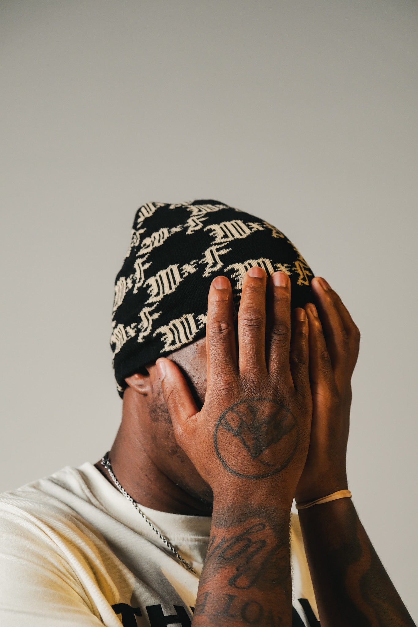 Model wearing a black and white repeated monogram patterned beanie