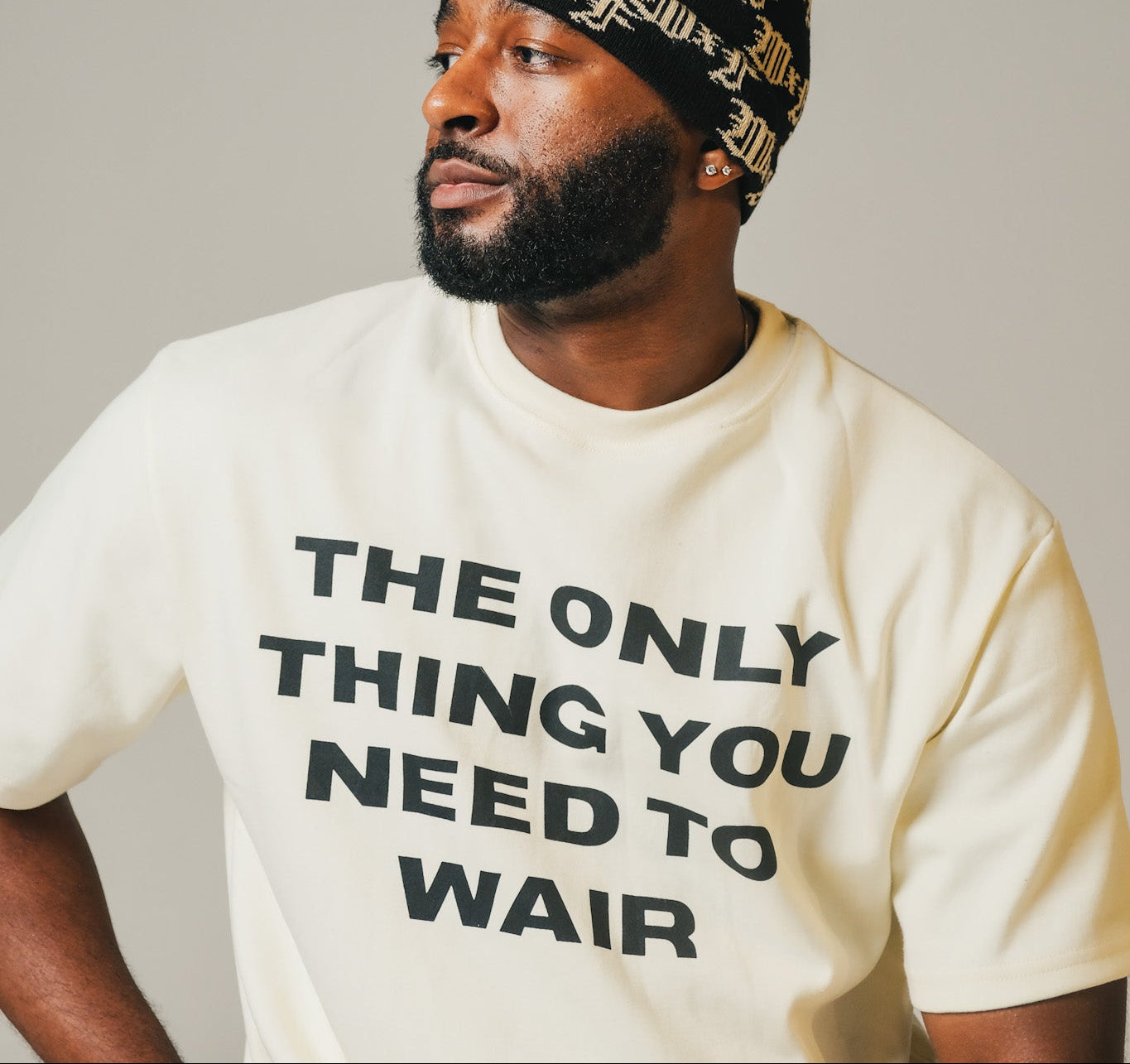 Model wearing a beanie and a t-shirt with text on a plain background