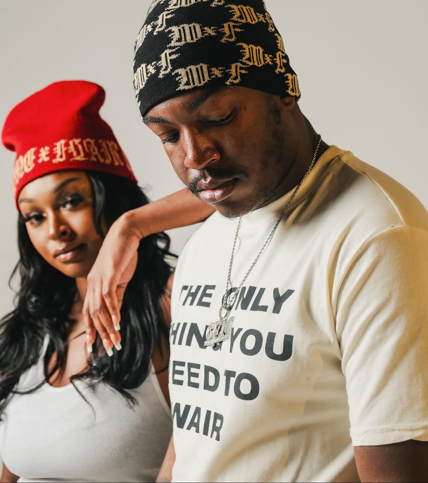 Two models wearing beanies and a t-shirt with text, standing close together.